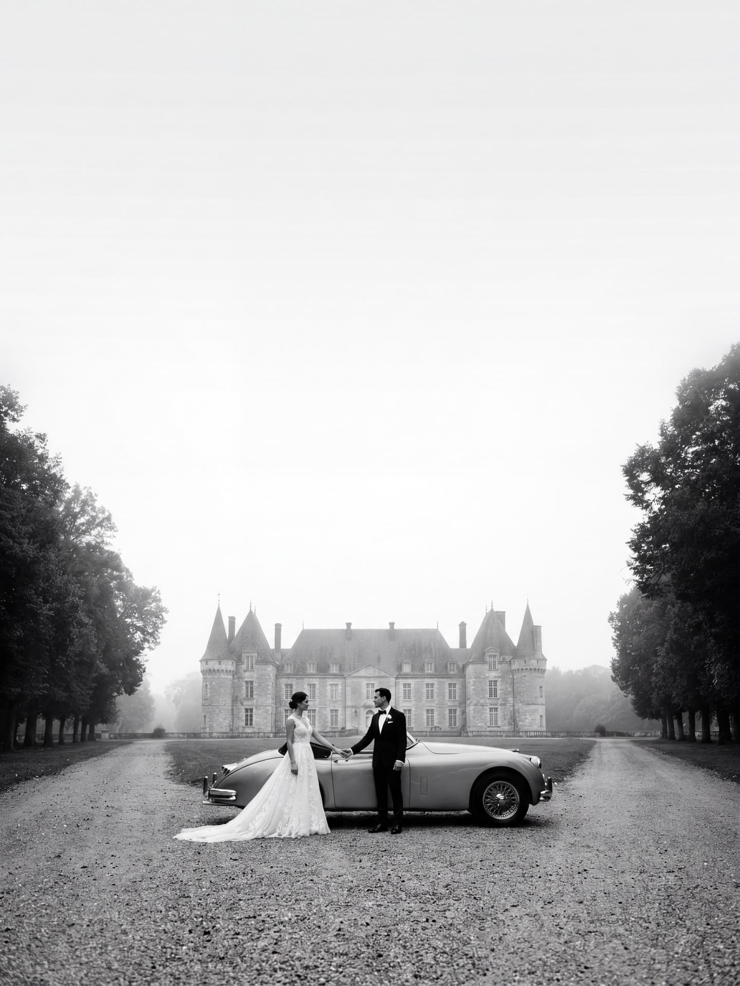 Photographe mariage luxe Genève — Couple de mariés en noir et blanc avec Jaguar vintage devant une allée de château — Benjamin Pierre Photographie