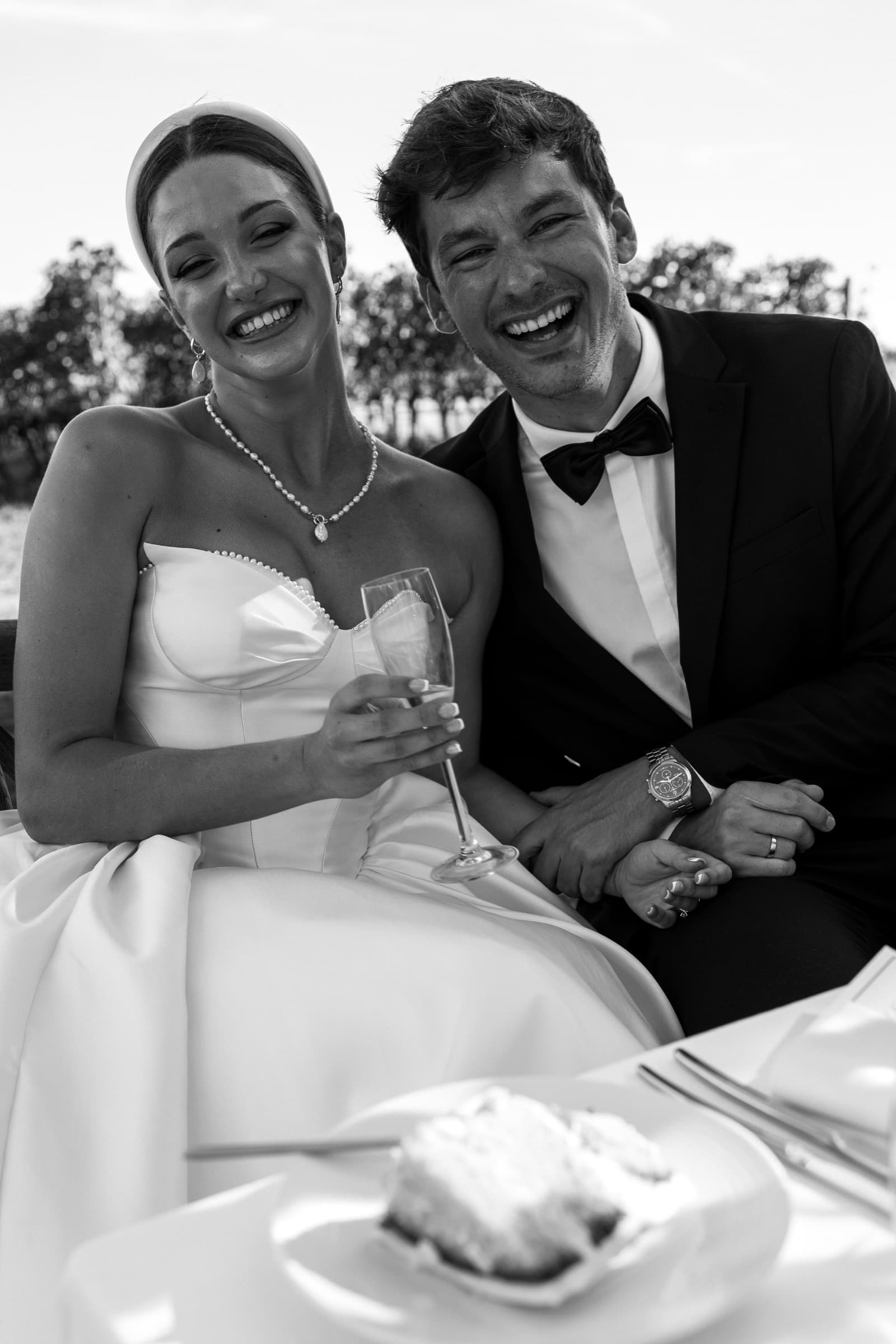 Le couple, coupe à la main, rires en noir et blanc — éditorial mariage Domaine La Capitaine, Gland