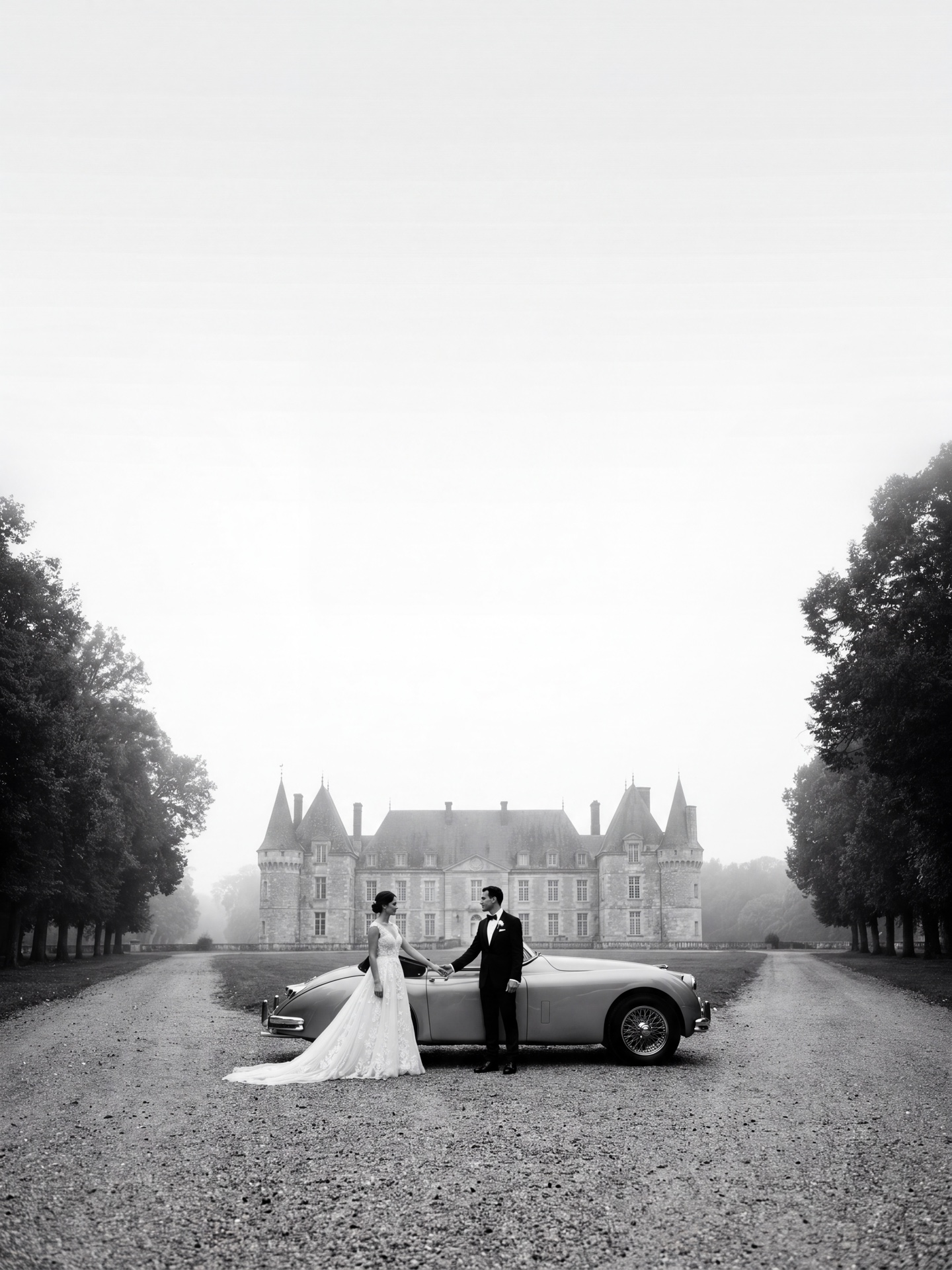 Photographe mariage luxe Genève — Couple de mariés en noir et blanc avec Jaguar vintage devant une allée de château — Benjamin Pierre Photographie